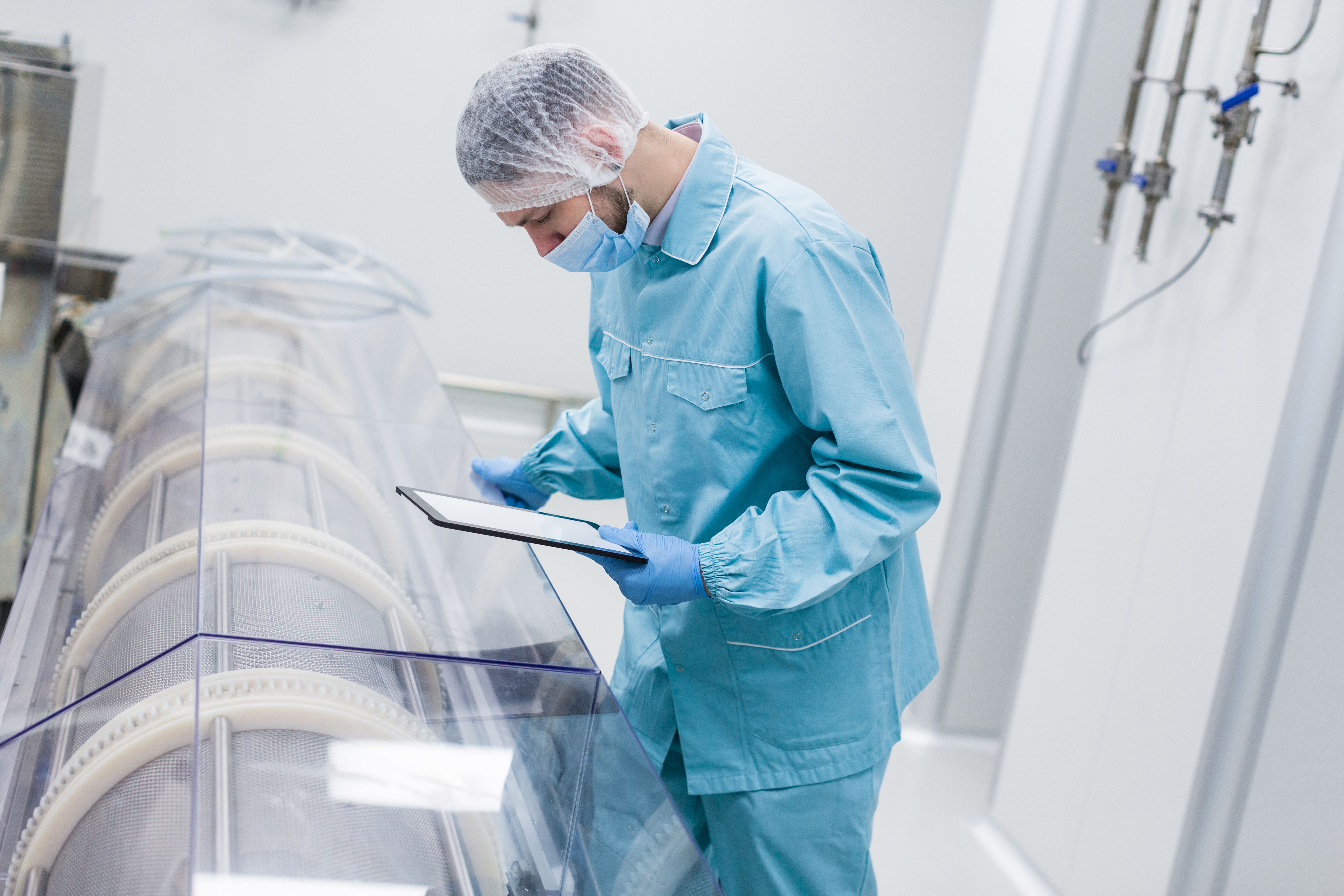 bended-caucasian-scientist-man-blue-lab-suit-make-notes-about-manufacture-machines