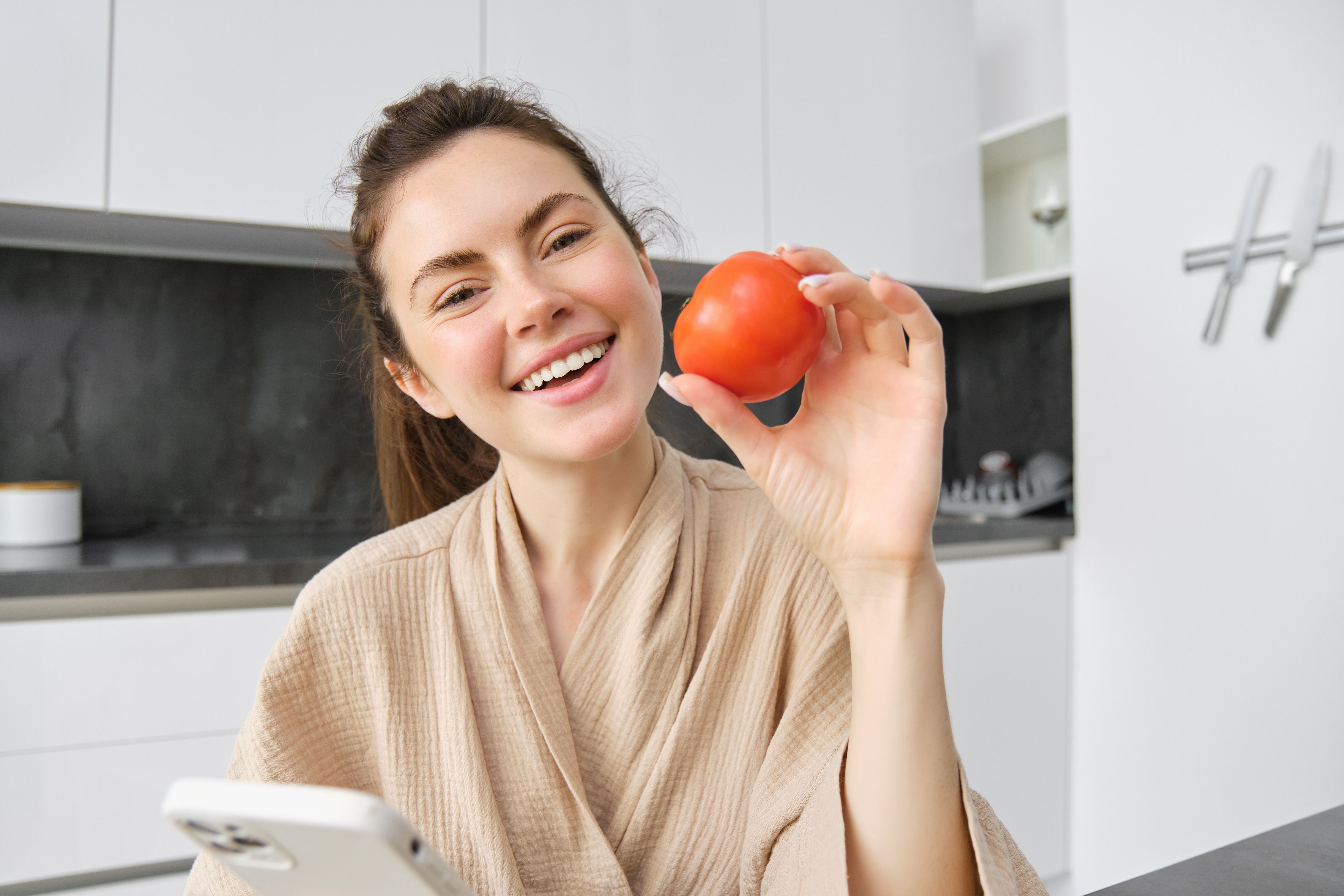 close-up-portrait-beautiful-smiling-woman-holding-fresh-tomato-sitting-kitchen-with-smartphone.jpg