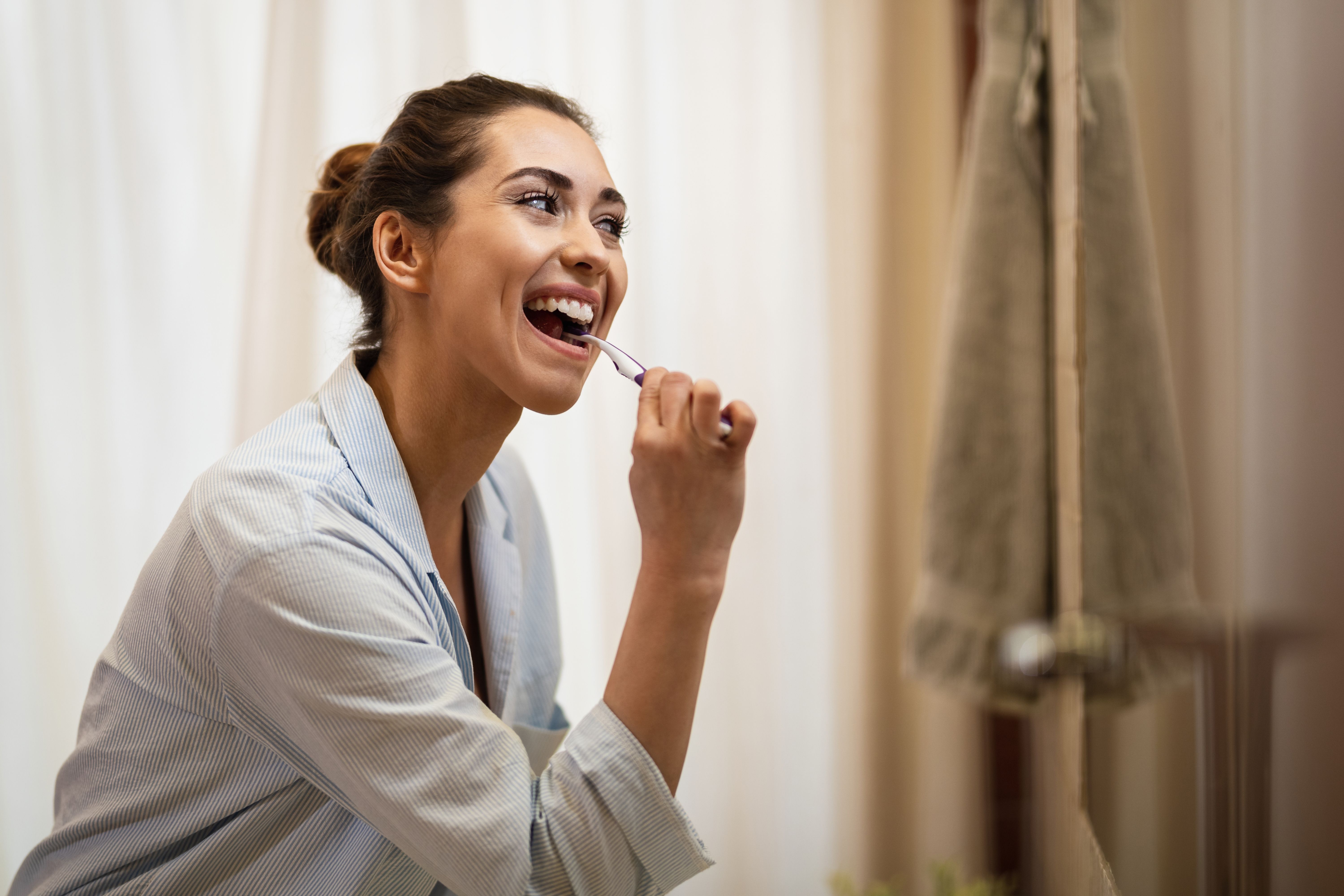 happy-woman-cleaning-her-teeth-with-toothbrush-morning.jpg