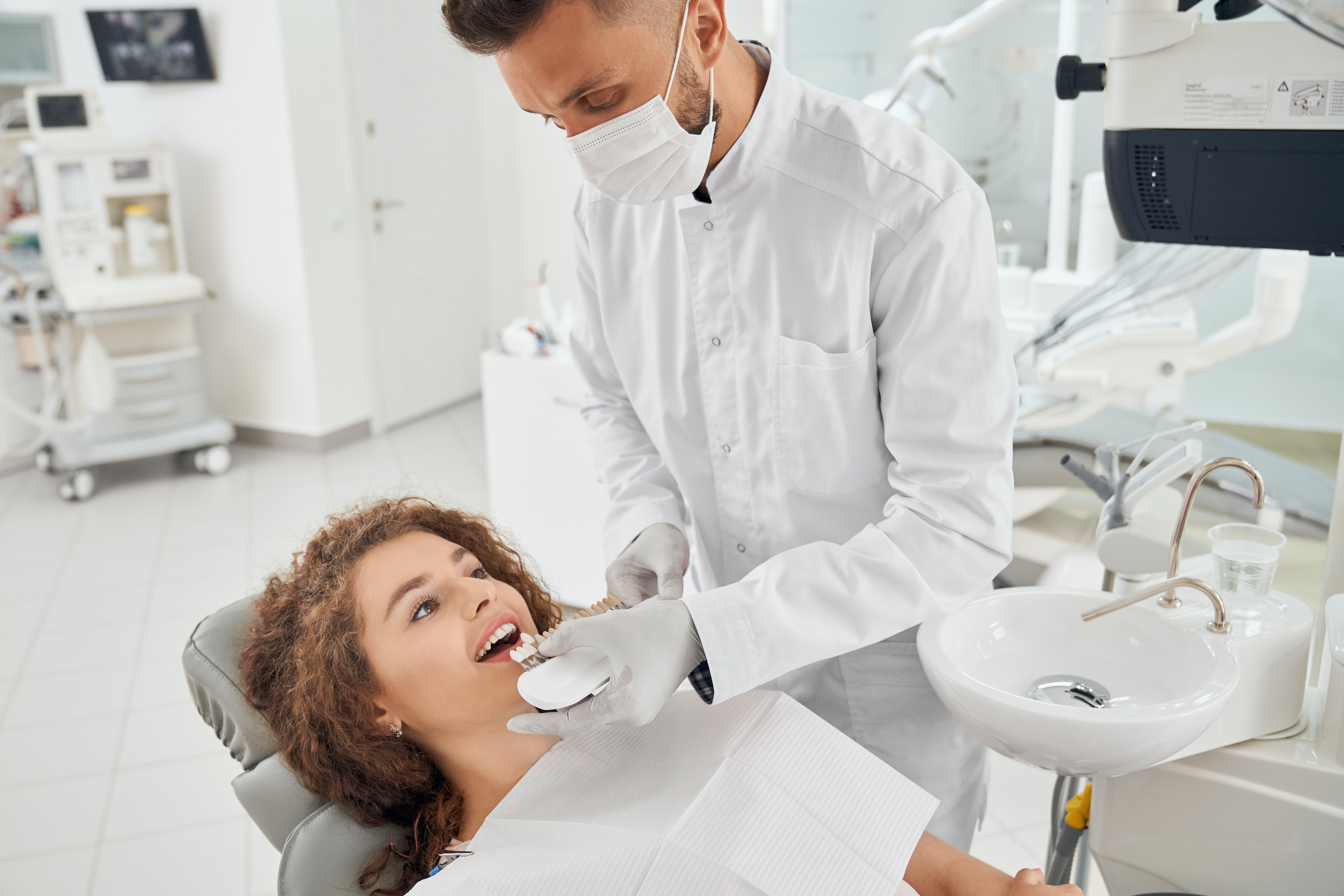 woman-smiling-while-male-dentist-keeping-teeth-color-range.jpg